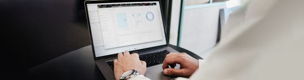 Businessman entering data on a laptop, symbolizing how smarter data empowers healthcare organizations to drive growth, align strategy, and control costs.