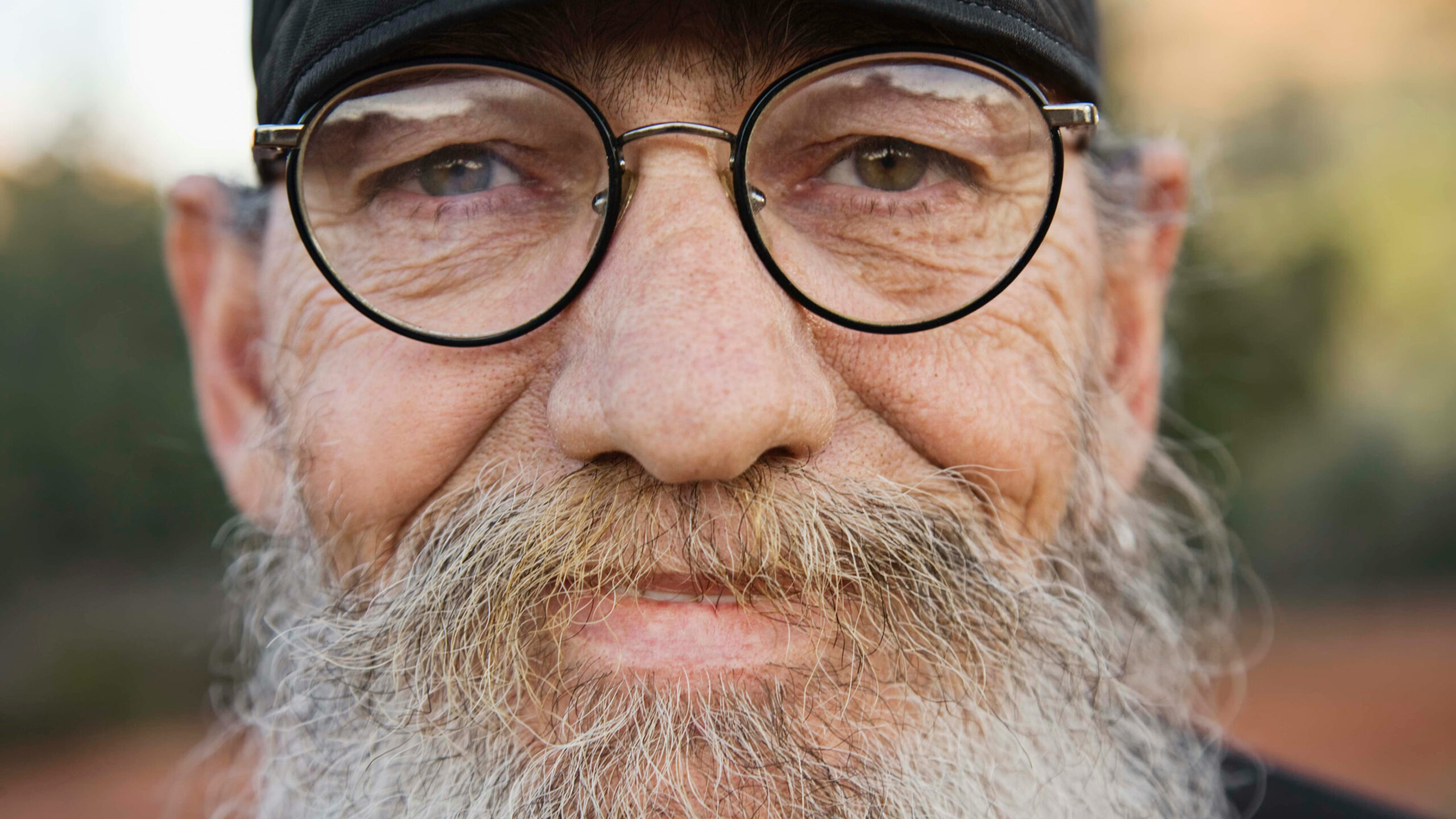 Close-up of an older man with glasses and a beard, looking calm and thoughtful
