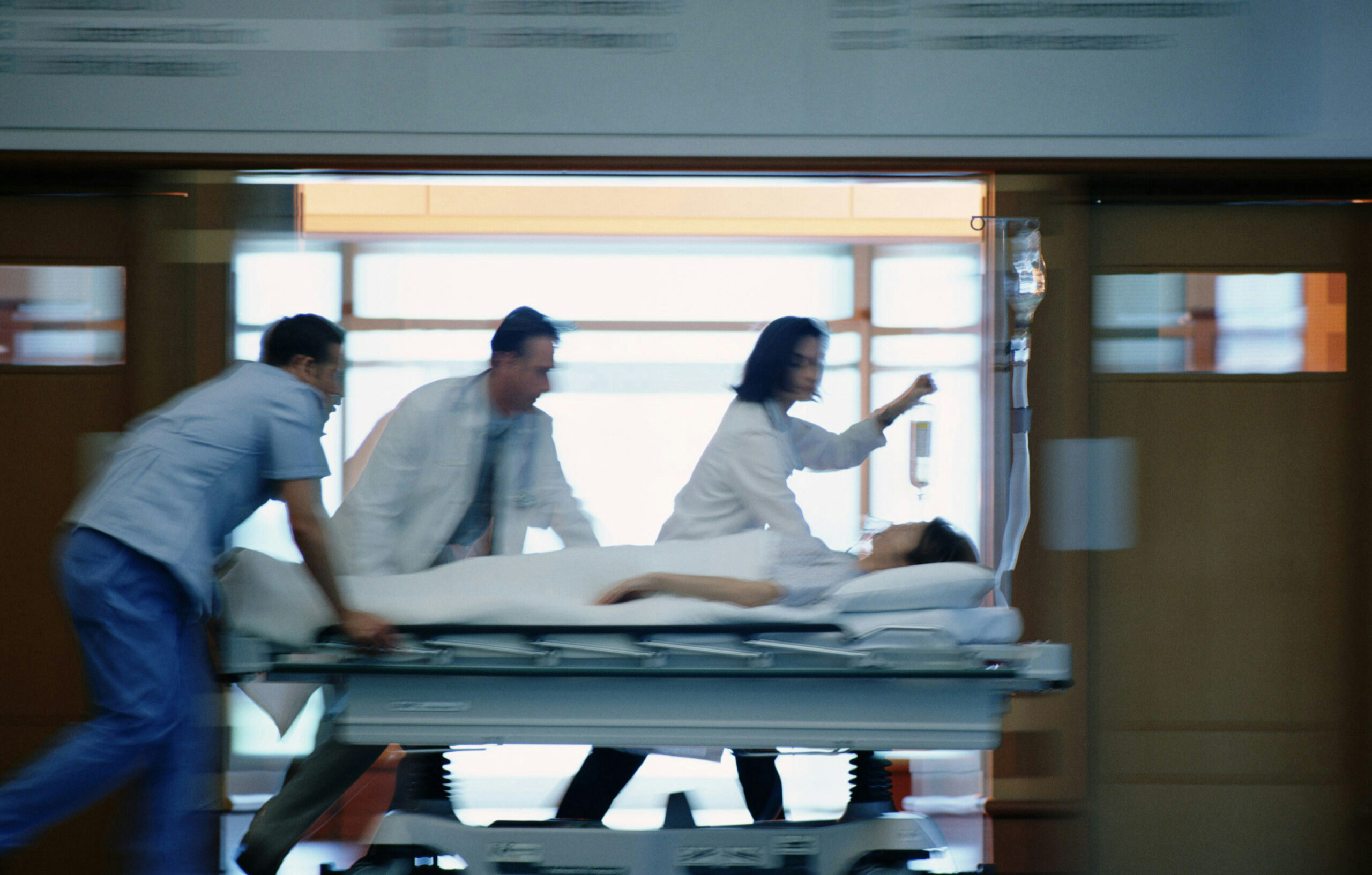 Medical team rushing a patient on a hospital gurney through a hallway